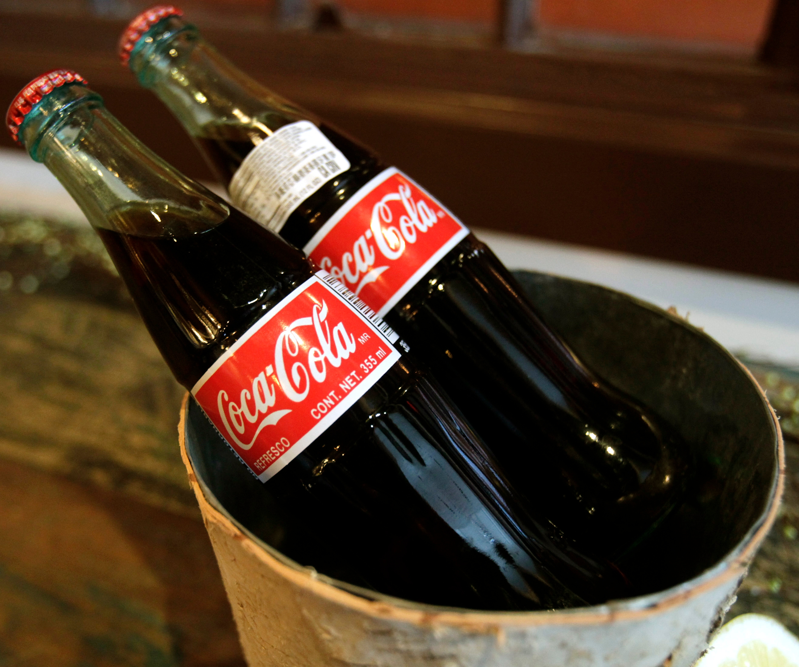 Two glass Coke bottles chilled in a metal bucket