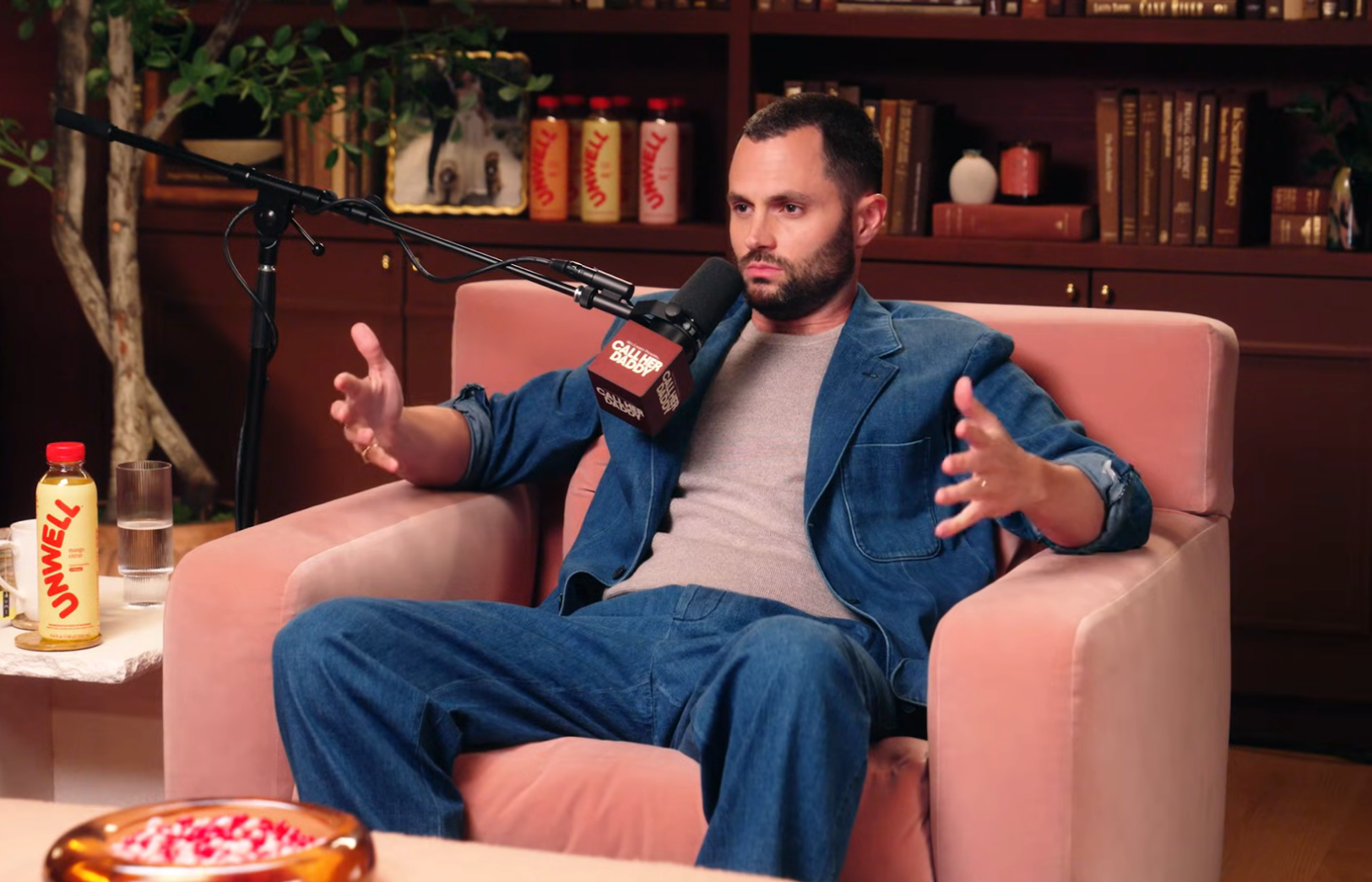 Penn Badgley speaking into a microphone on a podcast