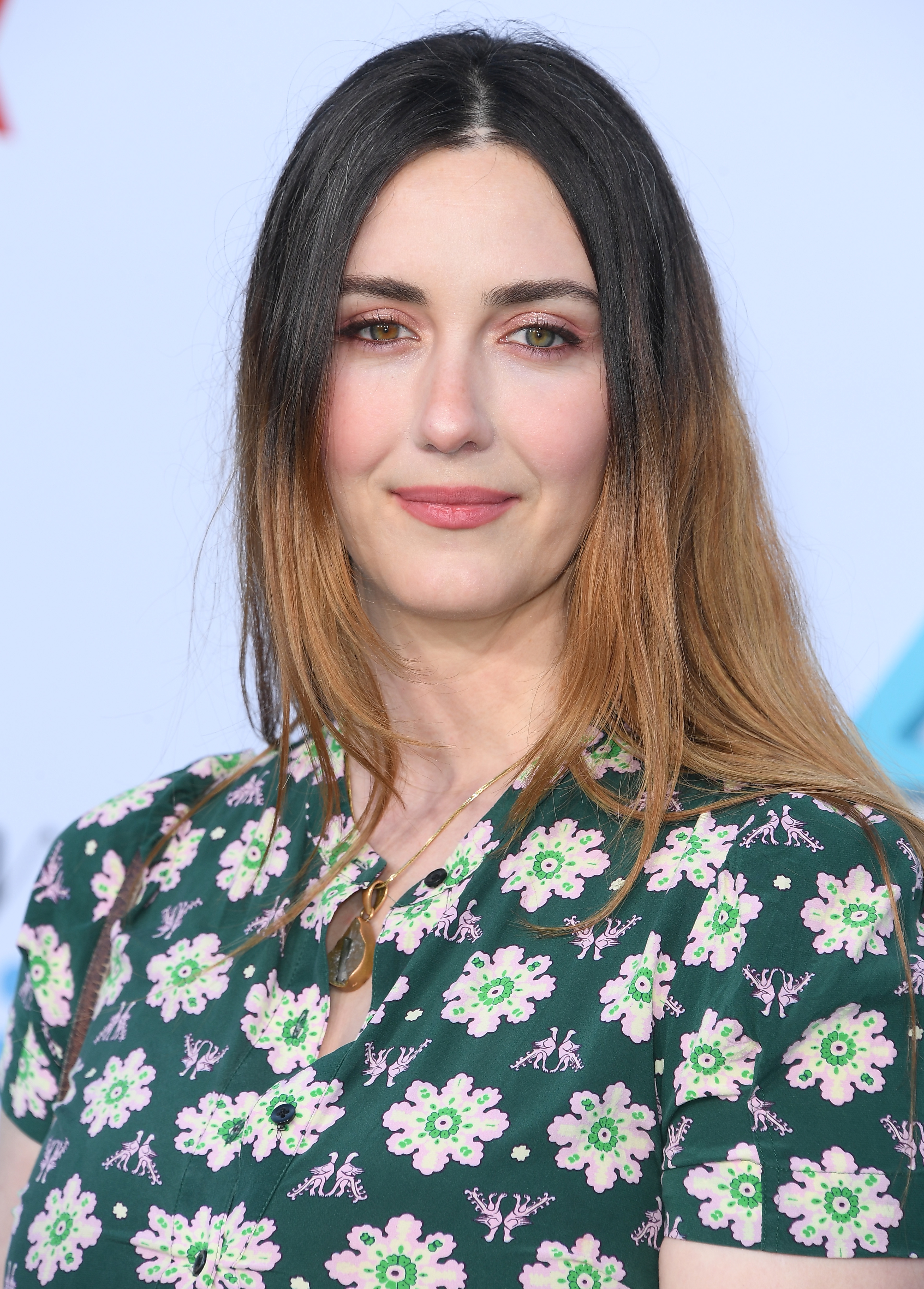 Person wearing a floral patterned dress, posing at a media event