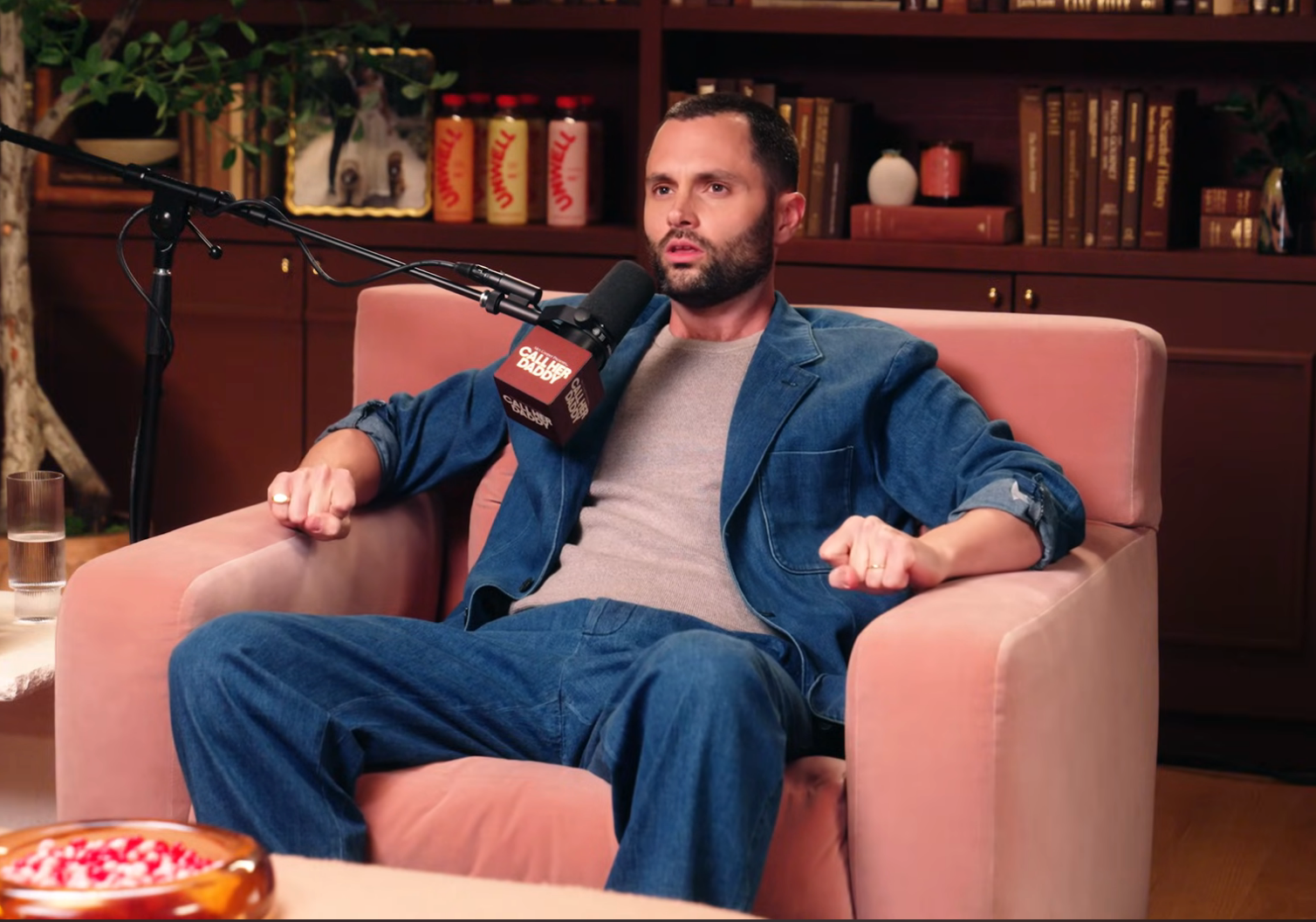 Penn Badgley speaking into a microphone on a podcast