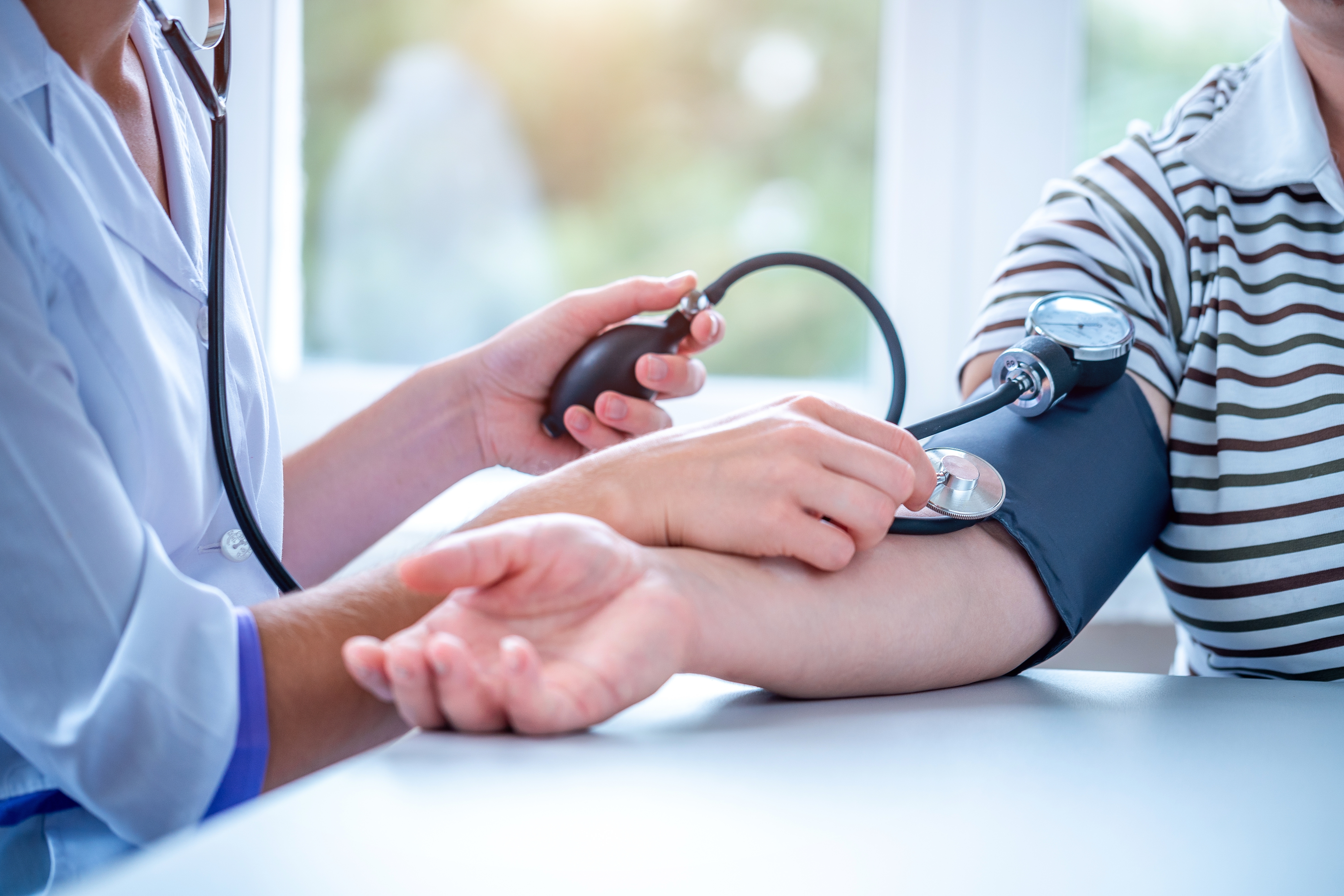 A healthcare professional uses a sphygmomanometer to measure a person's blood pressure at a clinic