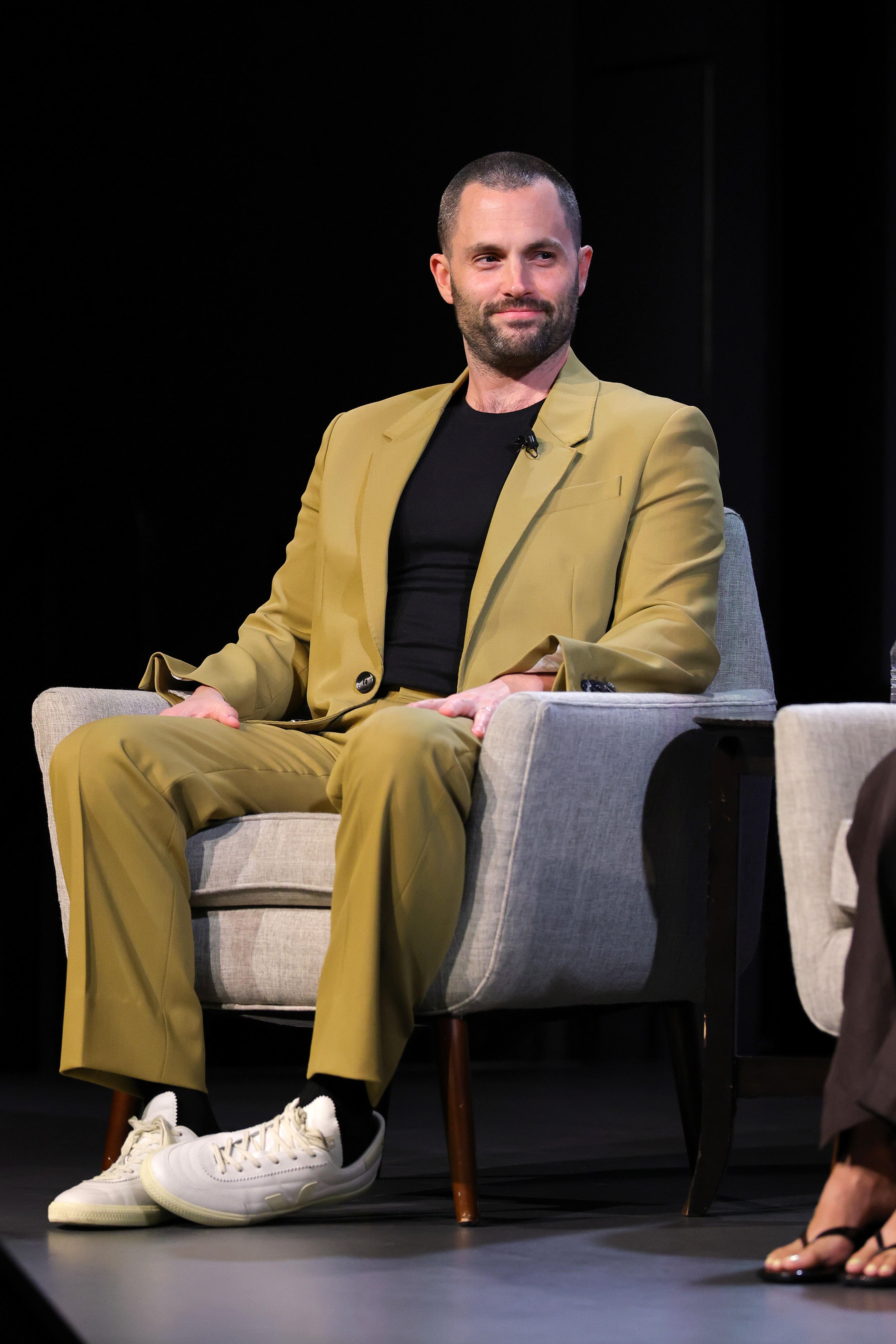 Penn Badgley seated on stage during a panel event
