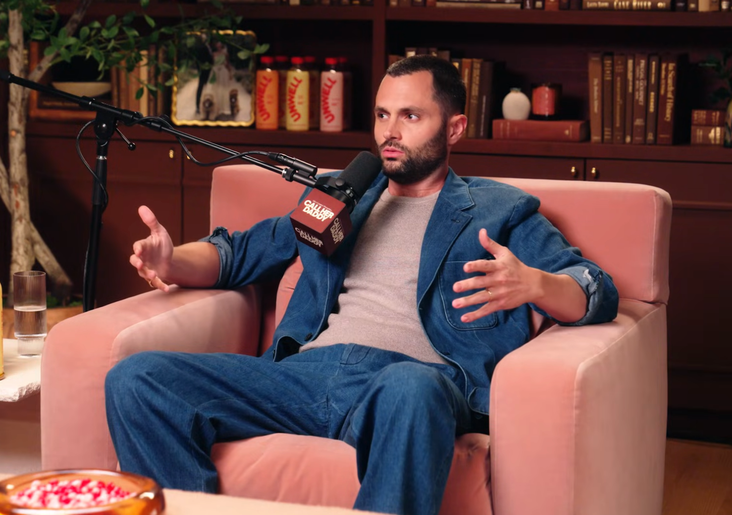 Penn Badgley speaking into a microphone on a podcast