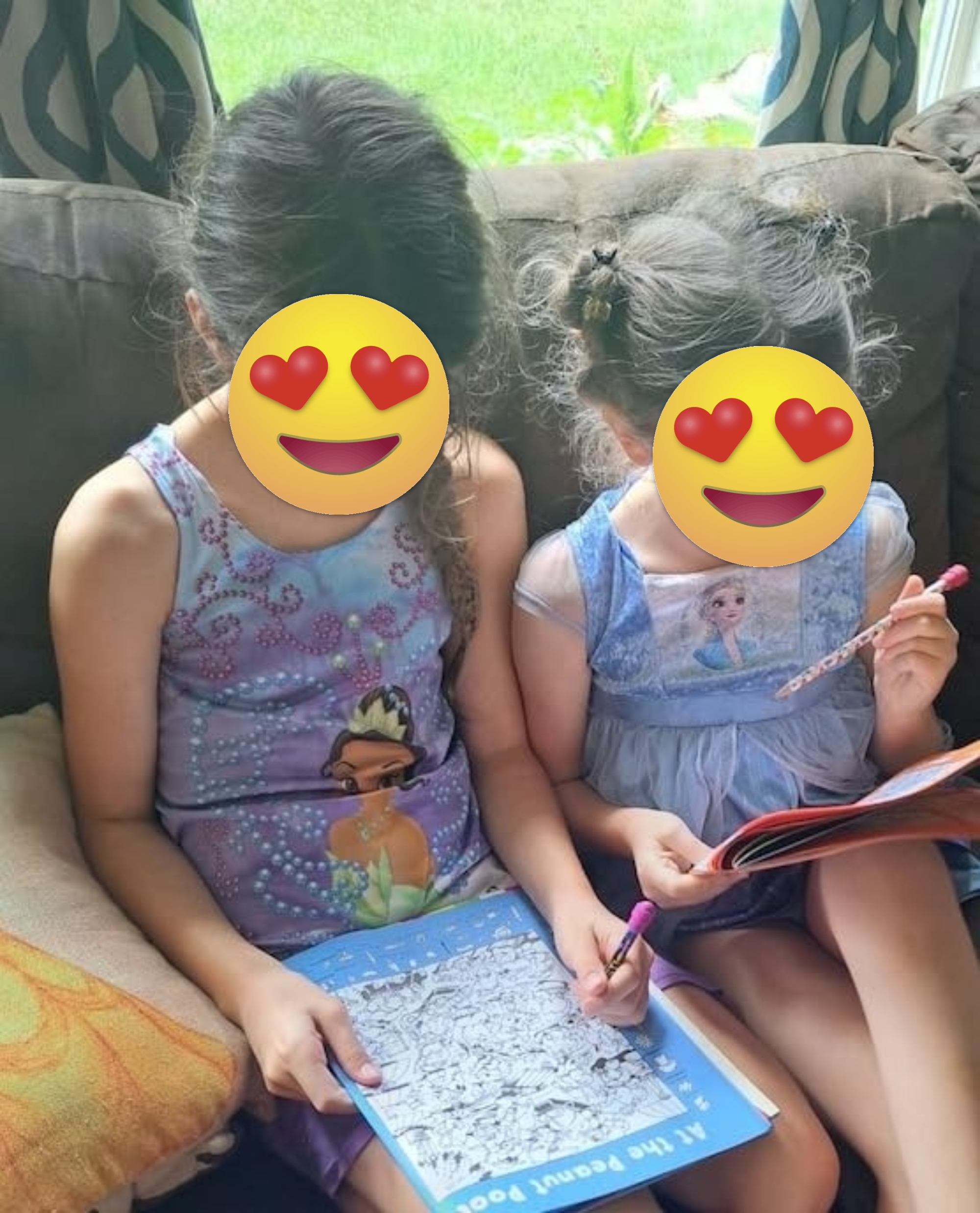 Two young children sit on a couch, focused on seek and find books featuring animated characters. They each hold a crayon