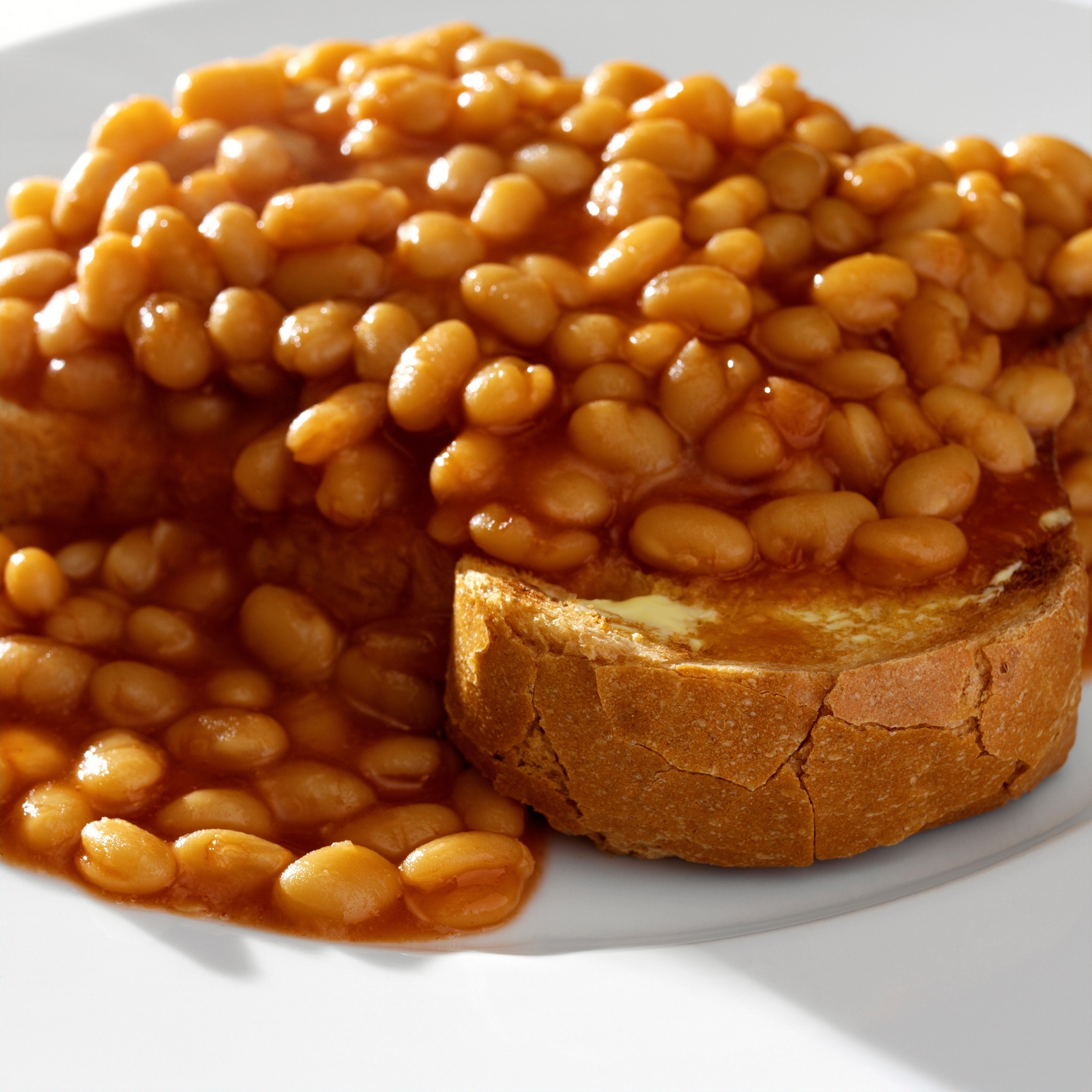 Baked beans poured over a slice of bread on a white plate, as commonly seen in humorous internet food trends