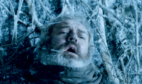 Hodor from "Game of Thrones" distressed, lying on a snow-covered ground with branches around him