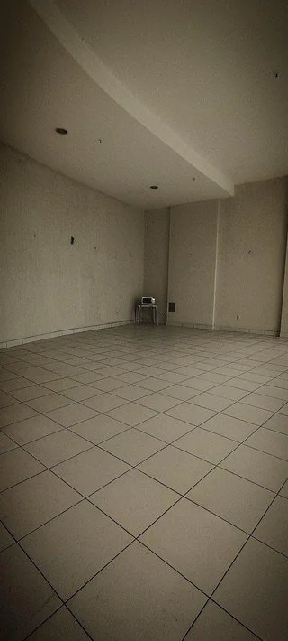 Empty room with tiled floor, bare walls, and a single chair in the corner