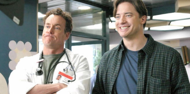 Ben and Cox from "Scrubs" stand together, Ben is smiling and Cox has his arms folded