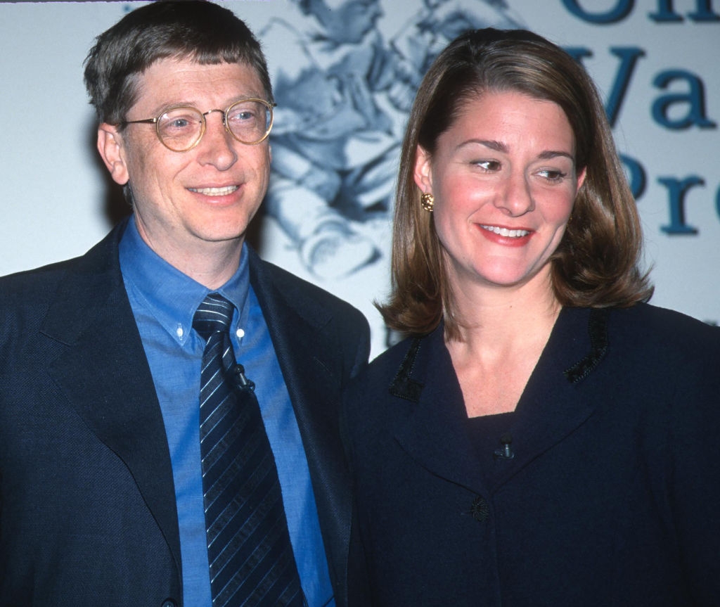 A couple in suits smile together at an event