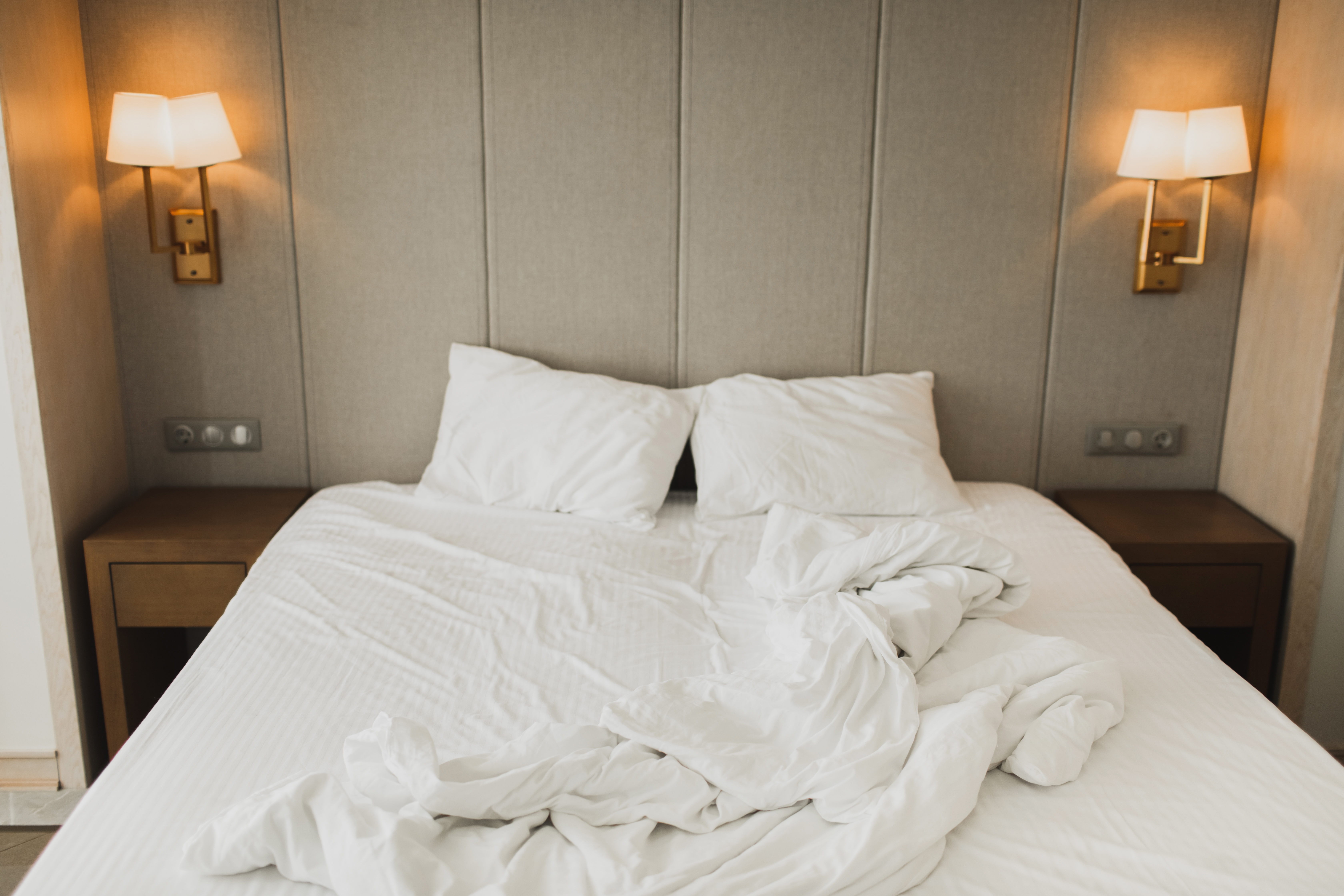 Unmade bed with pillows and tangled sheets in a cozy bedroom setting