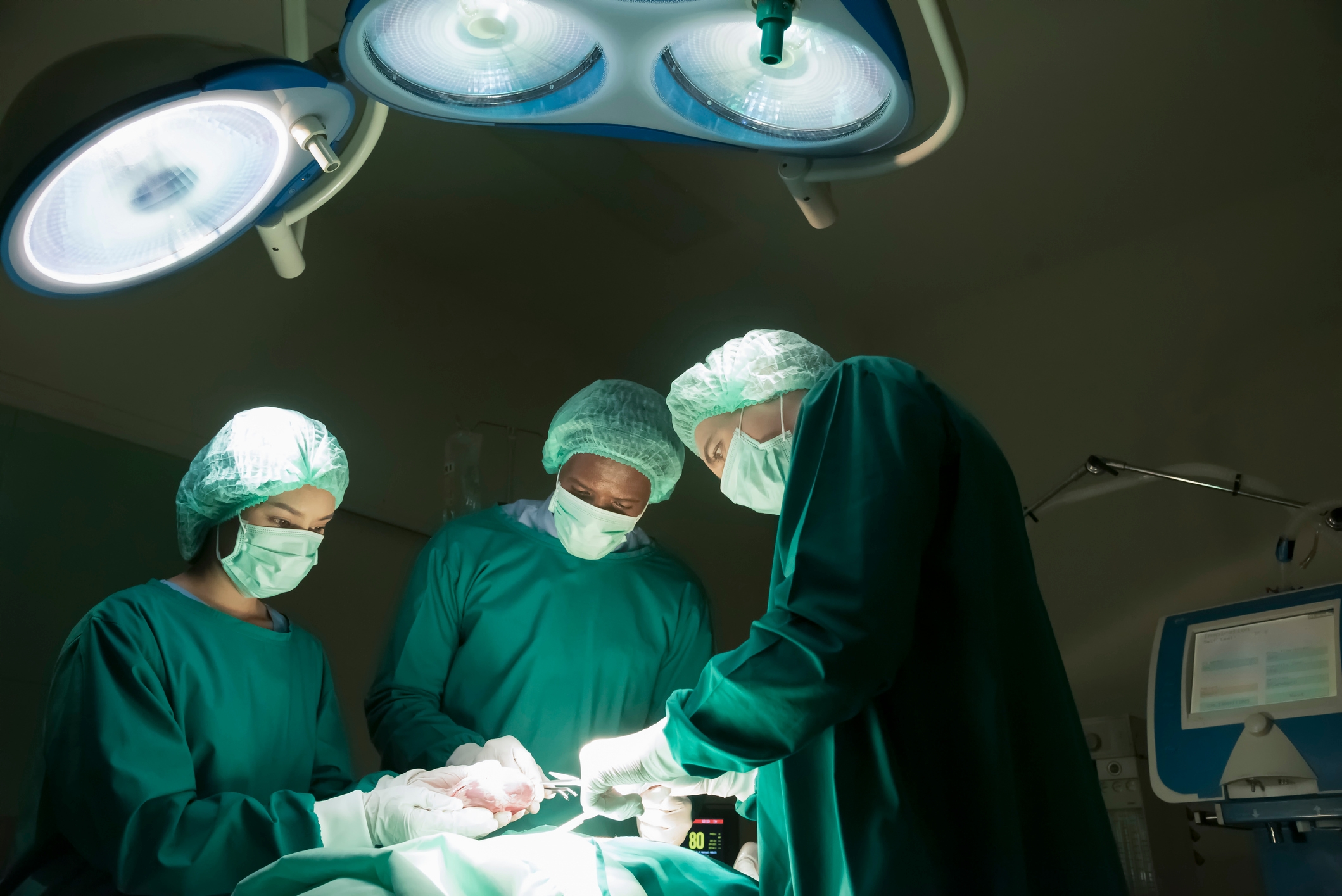 Surgeons focused on performing an operation in a well-lit operating room