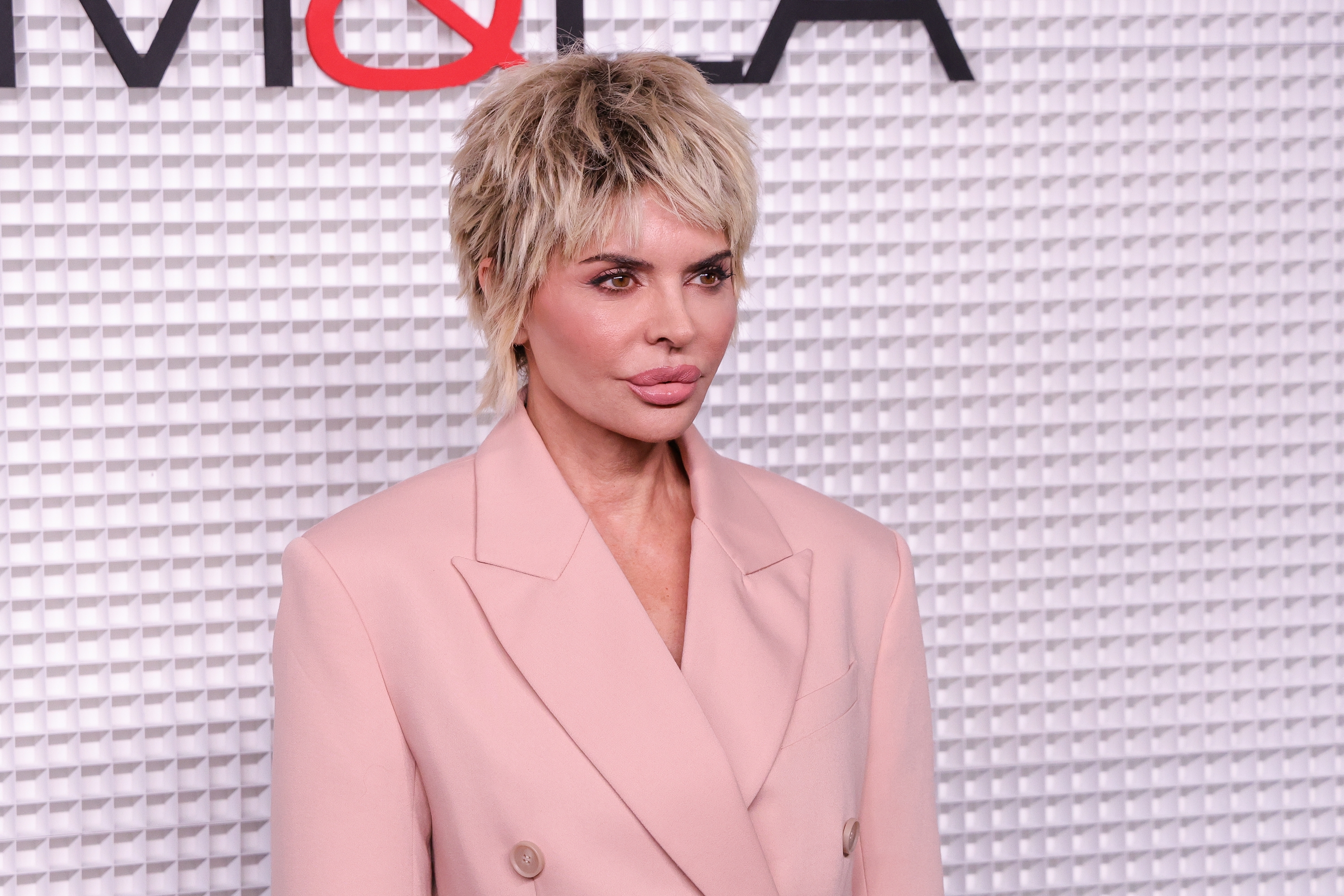 Lisa Rinna in a stylish double-breasted suit jacket on a patterned backdrop at a formal event