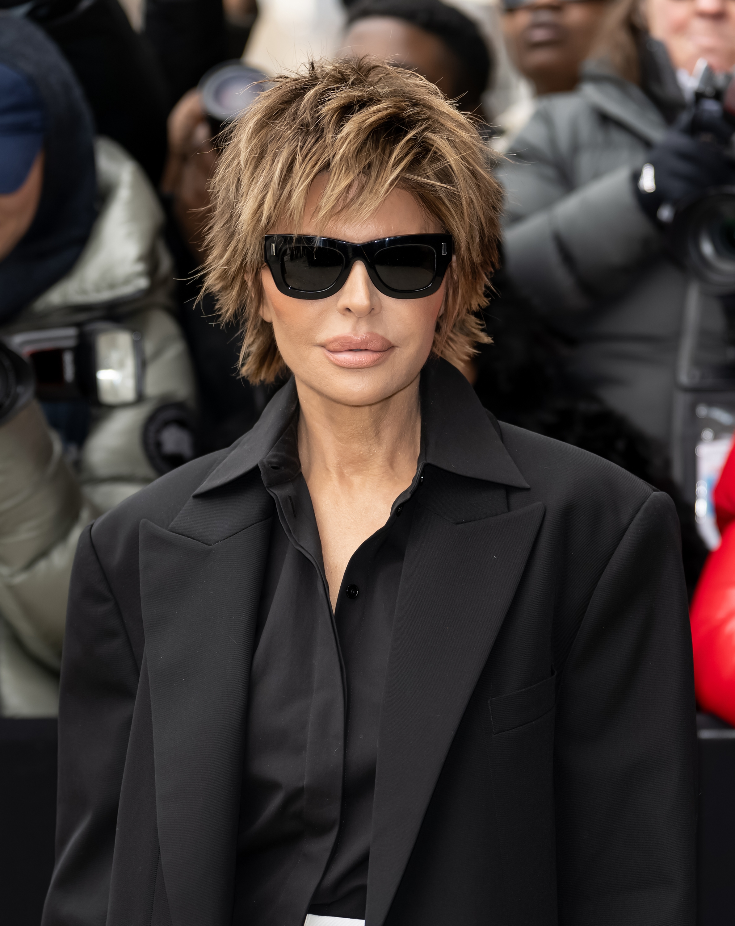 Lisa Rinna with a short haircut wearing a black oversized blazer and sunglasses, standing in front of a crowd outside