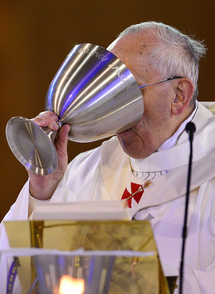 Pope Francis in ceremonial attire drinks from a large chalice during a service
