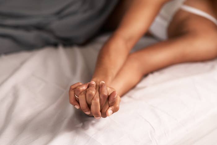 Two people lying in bed, holding hands, conveying intimacy and connection