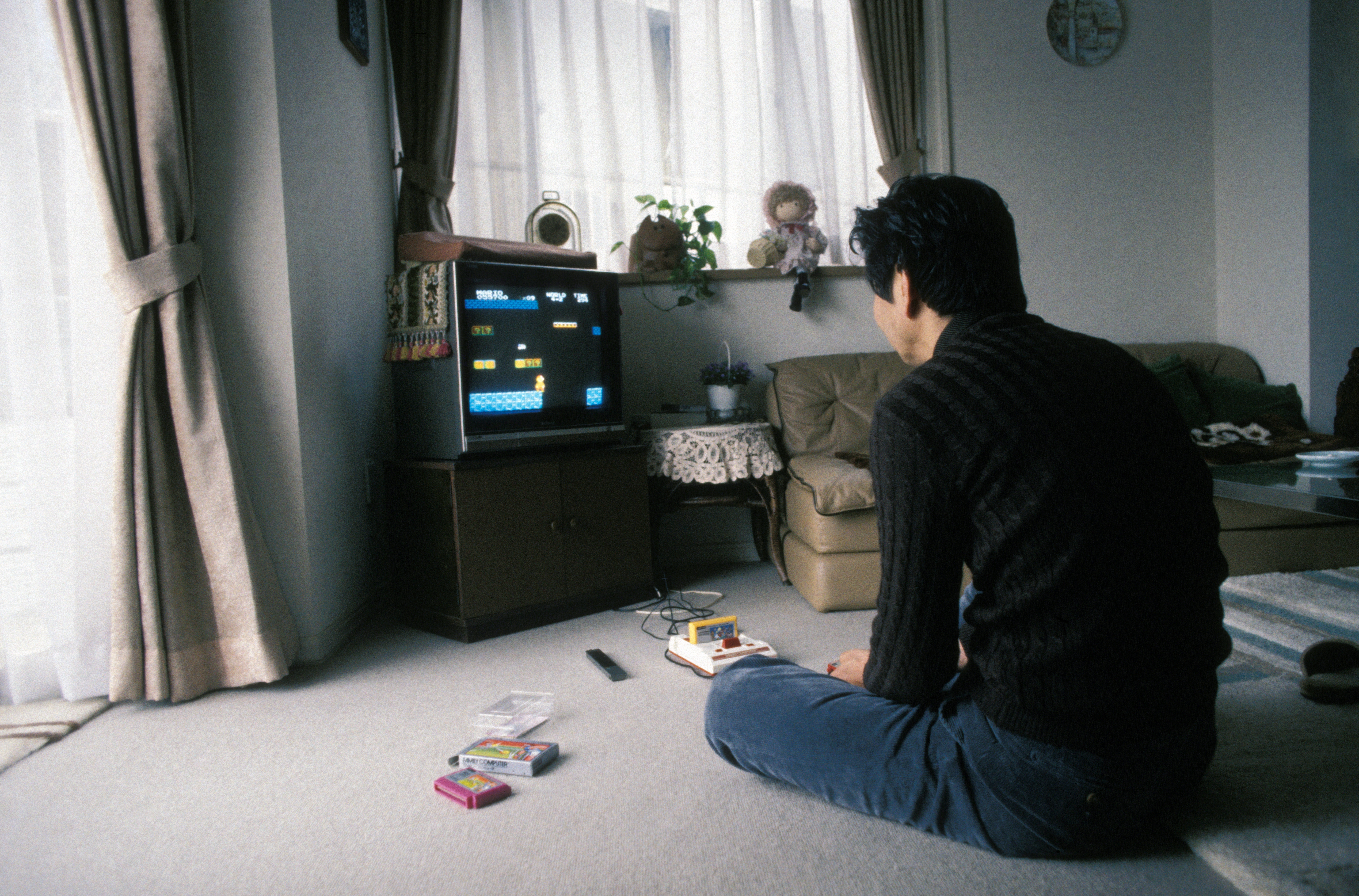 Person playing a retro video game on a TV in a cozy living room