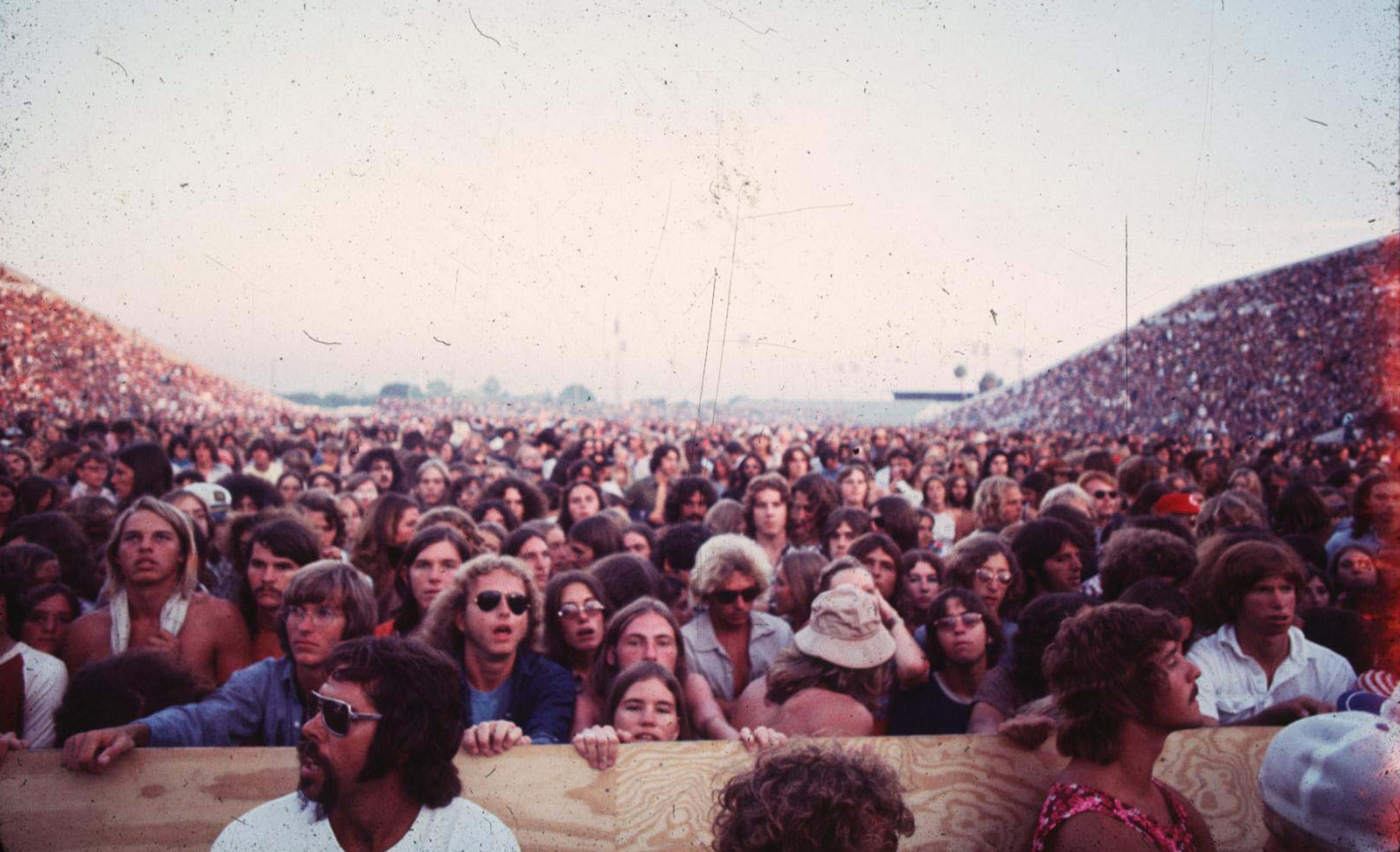 Large crowd of people attentively watching a concert at an outdoor venue