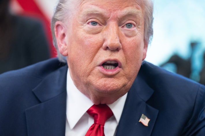 人物が正面を向いて話している。スーツにアメリカ国旗のバッジを付けている。