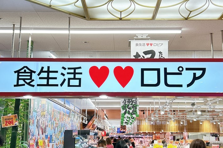 ロピアの食料品店内、買い物を楽しむ人々。店には多くの食材が並び、活気あふれる雰囲気。