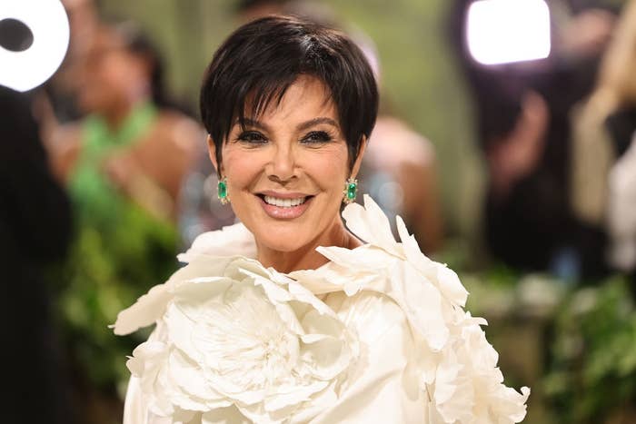 Person smiling at an event, wearing a floral-style outfit with statement earrings