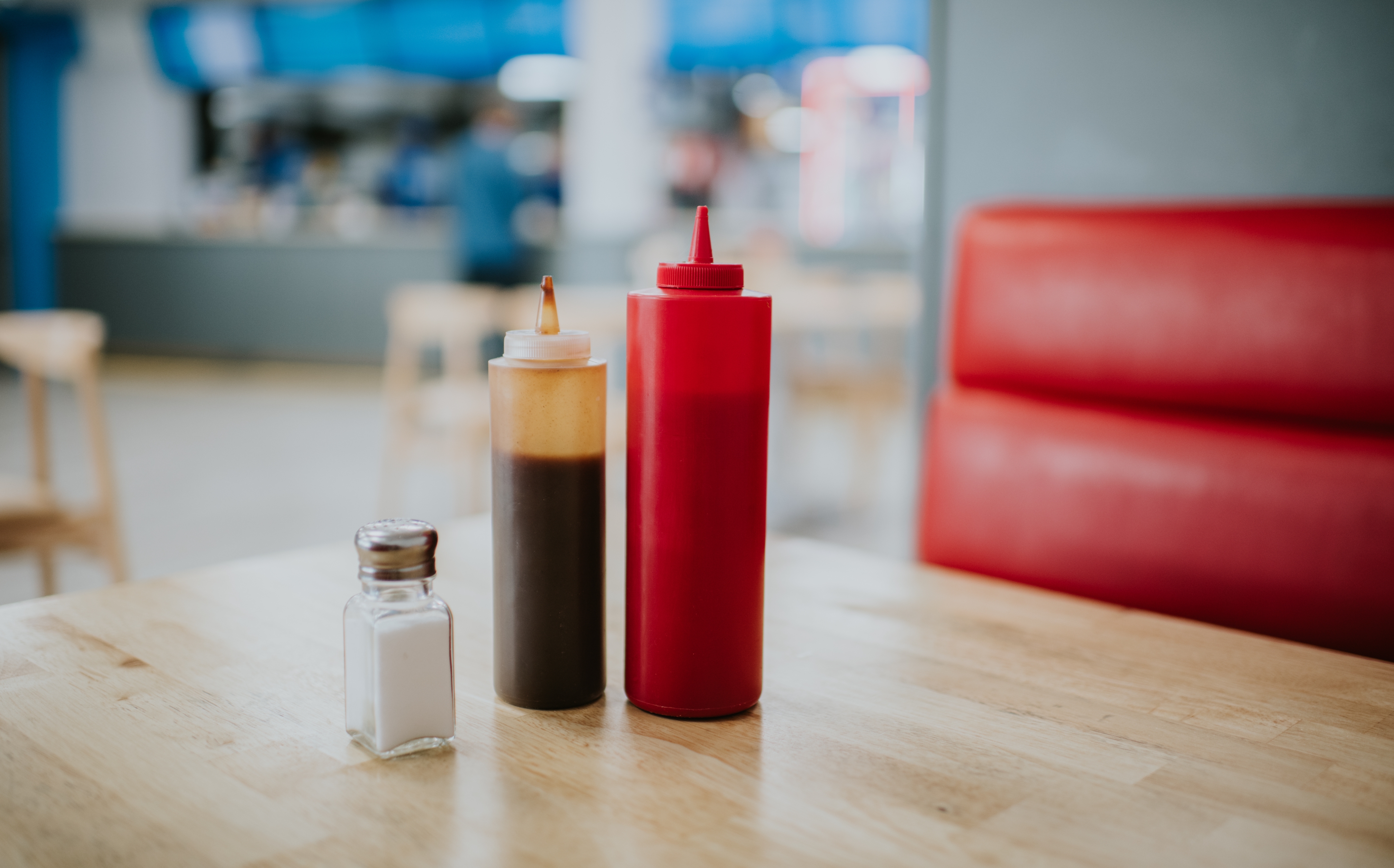 Salt, pepper, and ketchup bottles on a wooden diner table