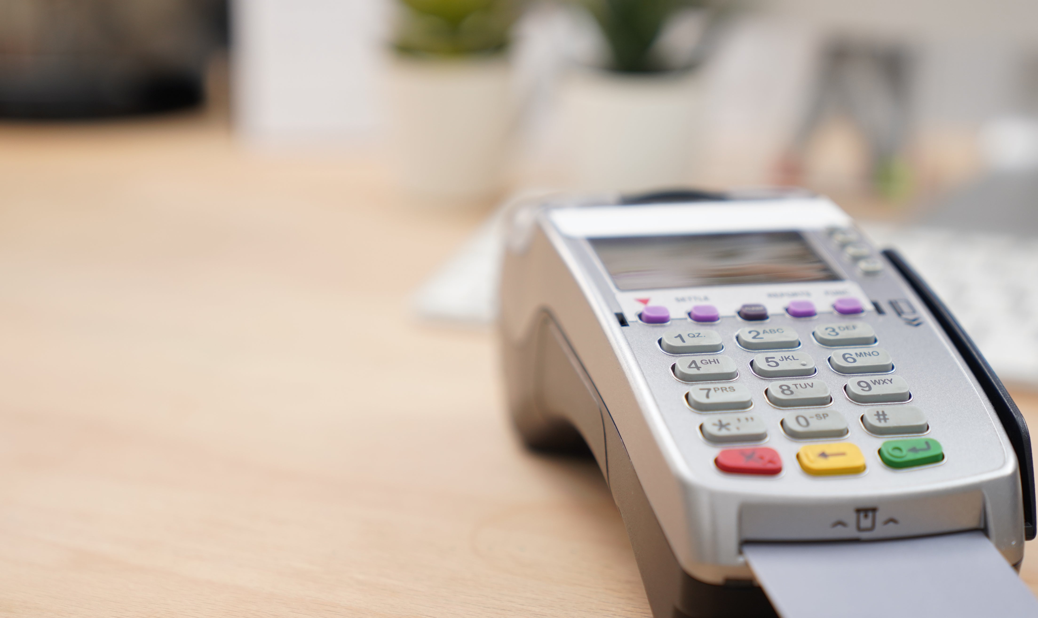 A credit card machine on a counter with a card inserted, in a minimalistic office setting
