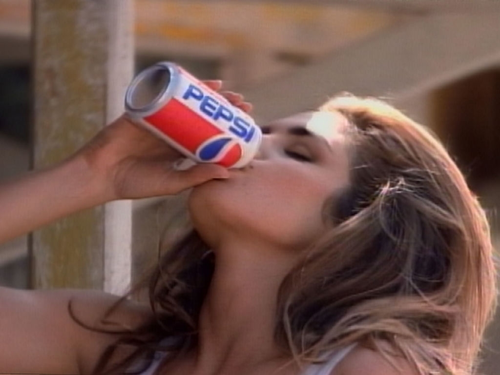 A person drinks from a Pepsi can, head tilted back