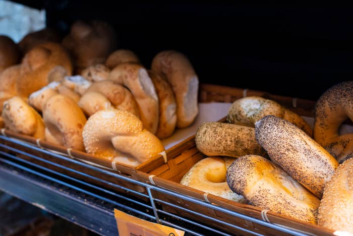 Bagels in a display rack, including plain and poppy seed varieties, arranged in wicker baskets