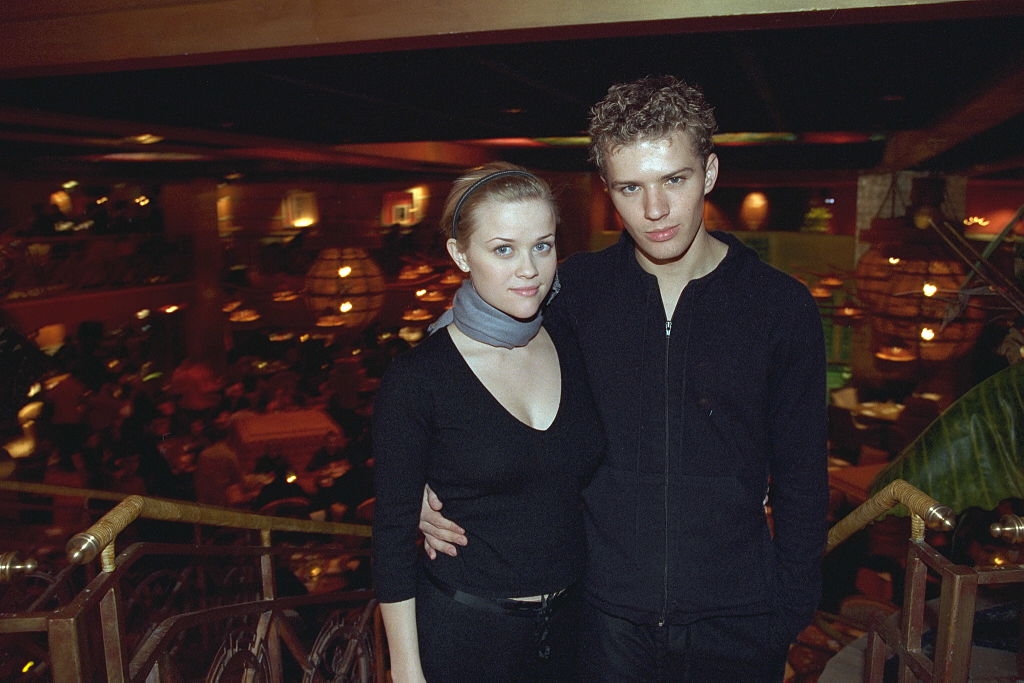 Two people posing together in a dimly lit venue, dressed in casual black attire