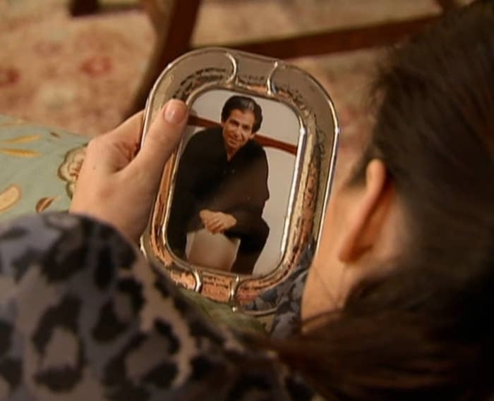 Khloé from the back, looking at a framed photo of Robert Kardashian Sr. sitting and smiling