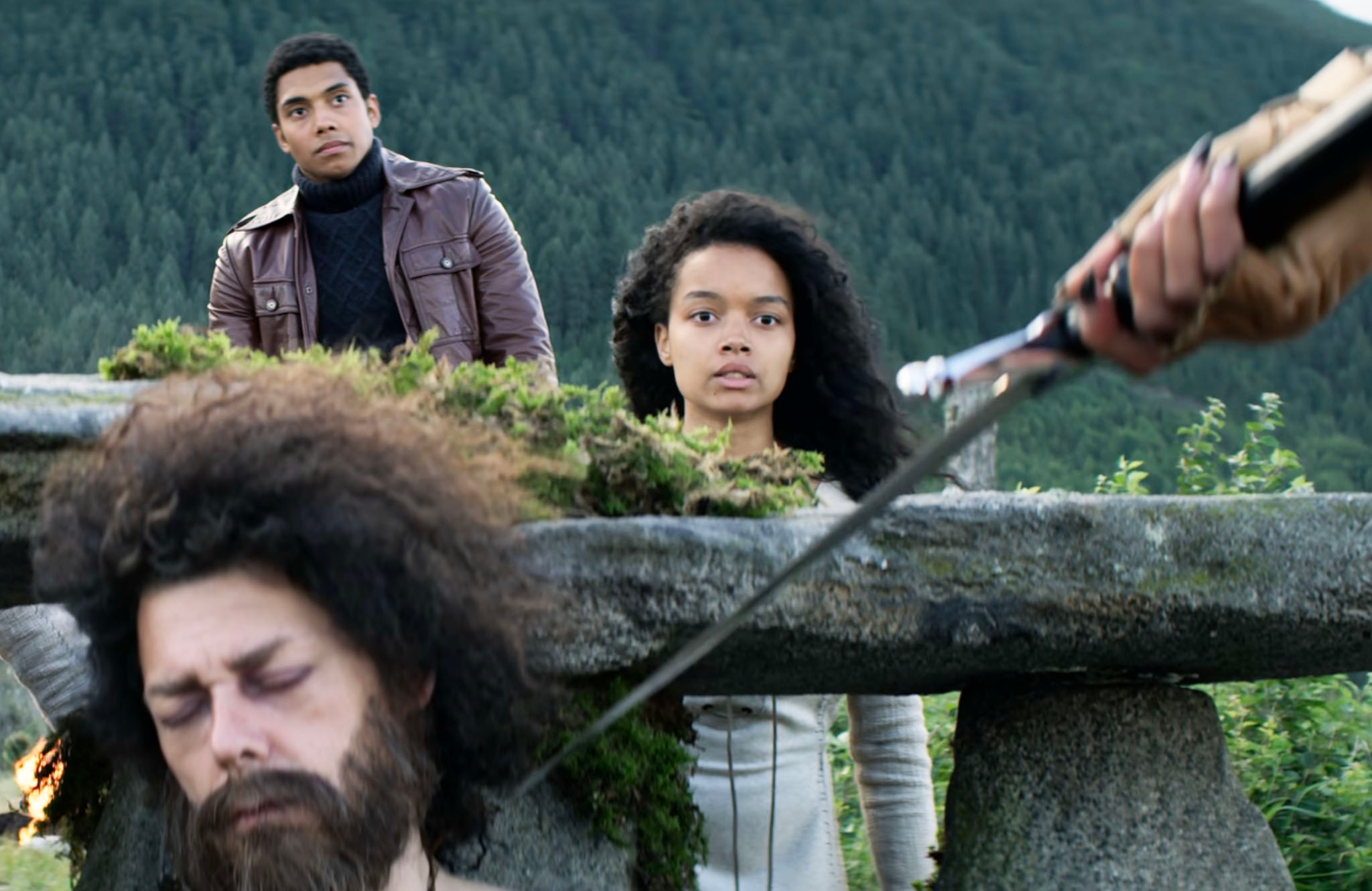 Whitney Peak in a scene from "Chilling Adventure of Sabrina" as she watches someone wielding a sword
