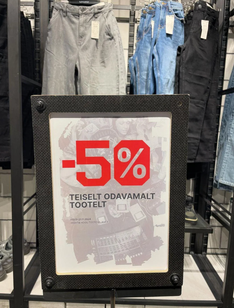 Store sign: "-5% off select products." Sign is displayed in front of various pants