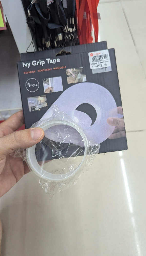 Person holding a pack of Ivy Grip Tape with labeled features: reusable, removable, washable, 1 roll