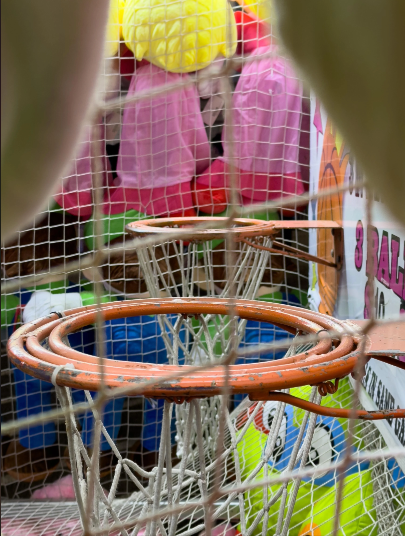 Basketball carnival game with three baskets and colorful stuffed toys in the background