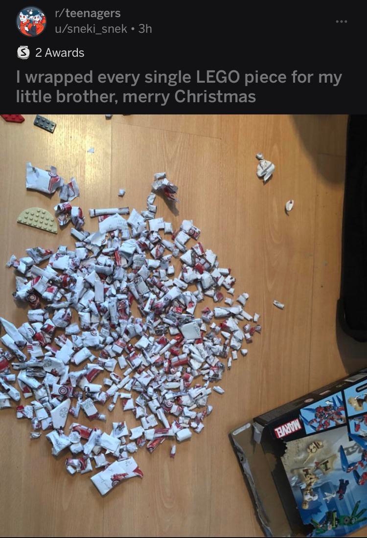 LEGO pieces individually wrapped in festive paper are scattered on a wooden floor next to an open box