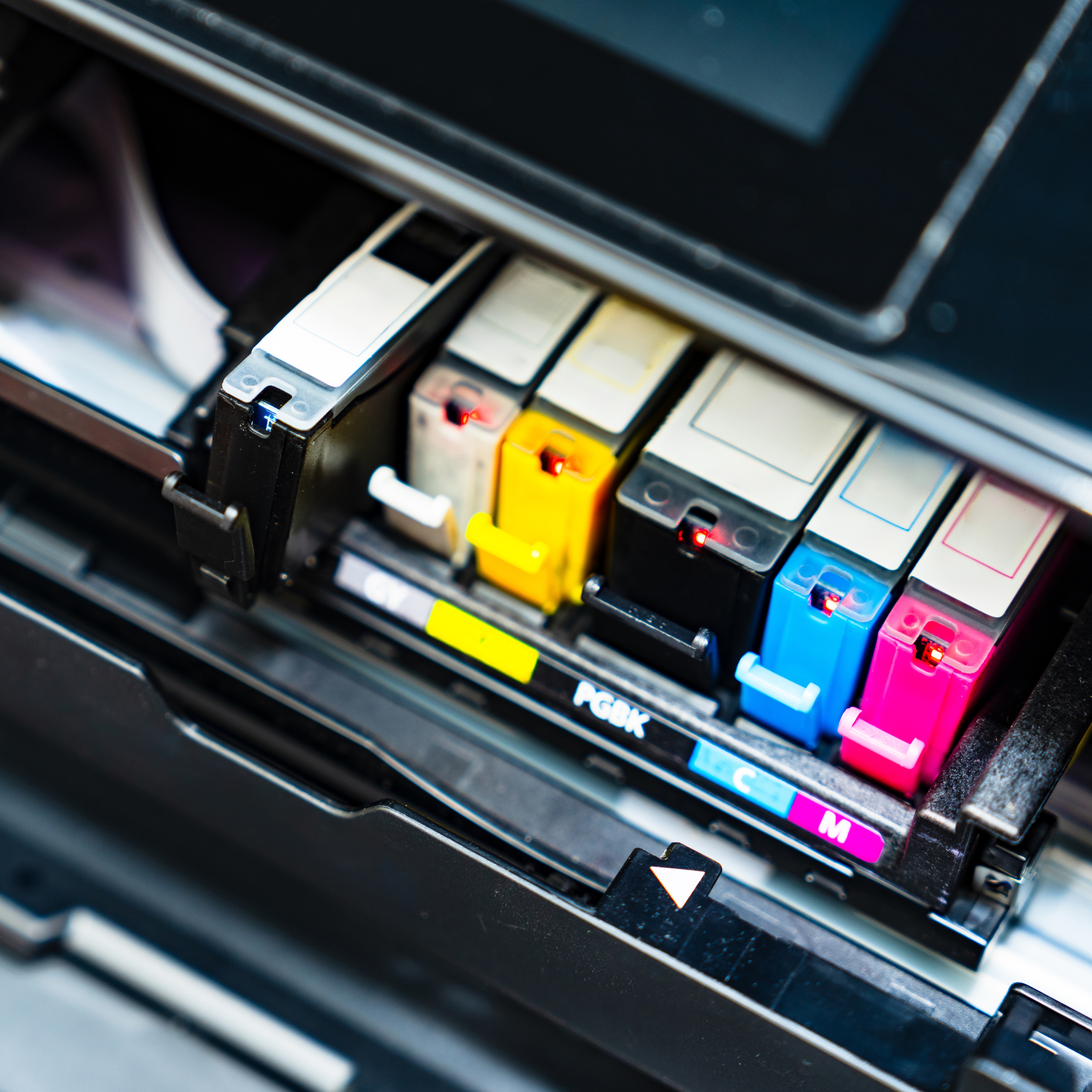 Printer ink cartridges installed in a printer, each with distinct labels indicating different ink colors, ready for printing