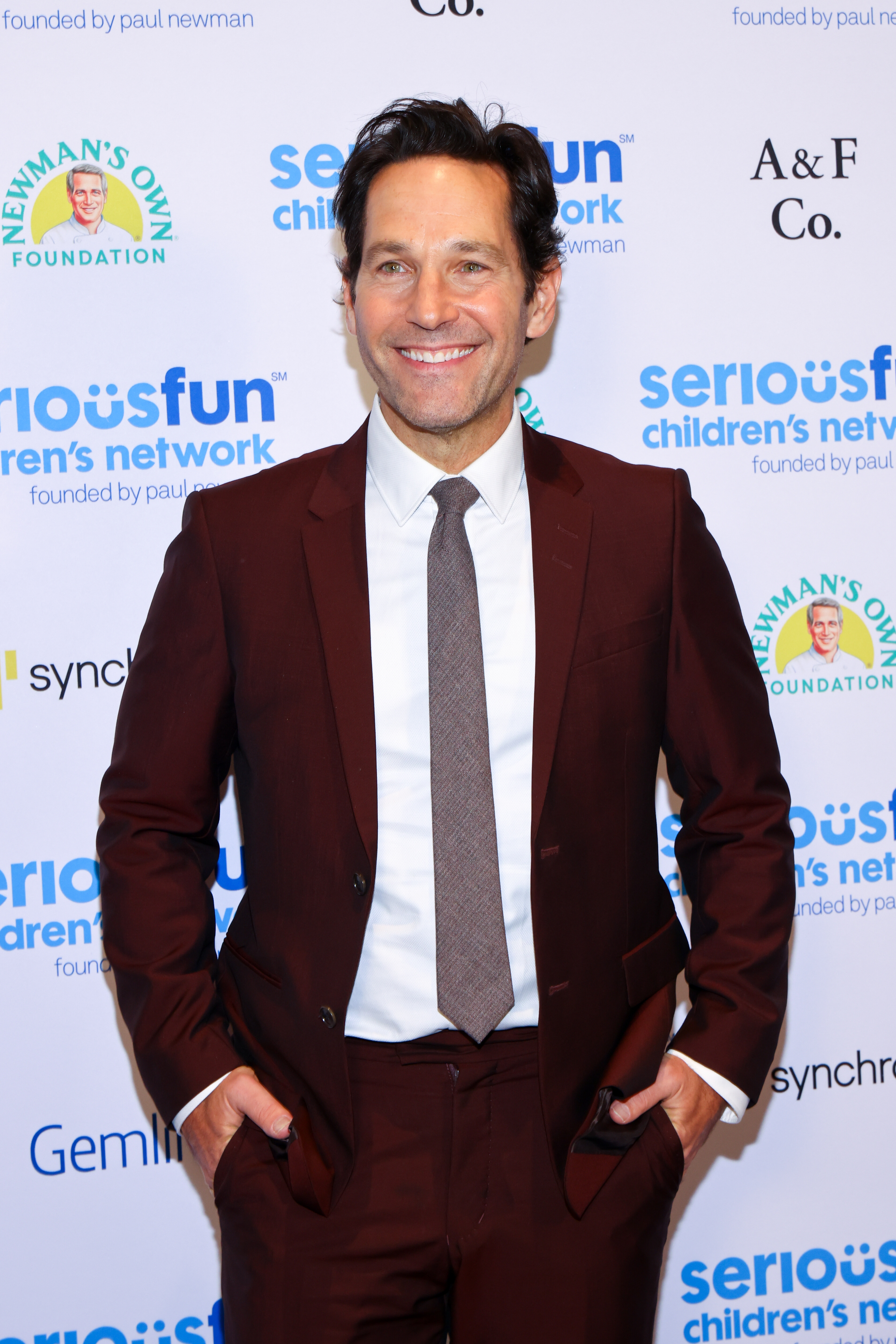 Person in a suit smiles at a charity event backdrop