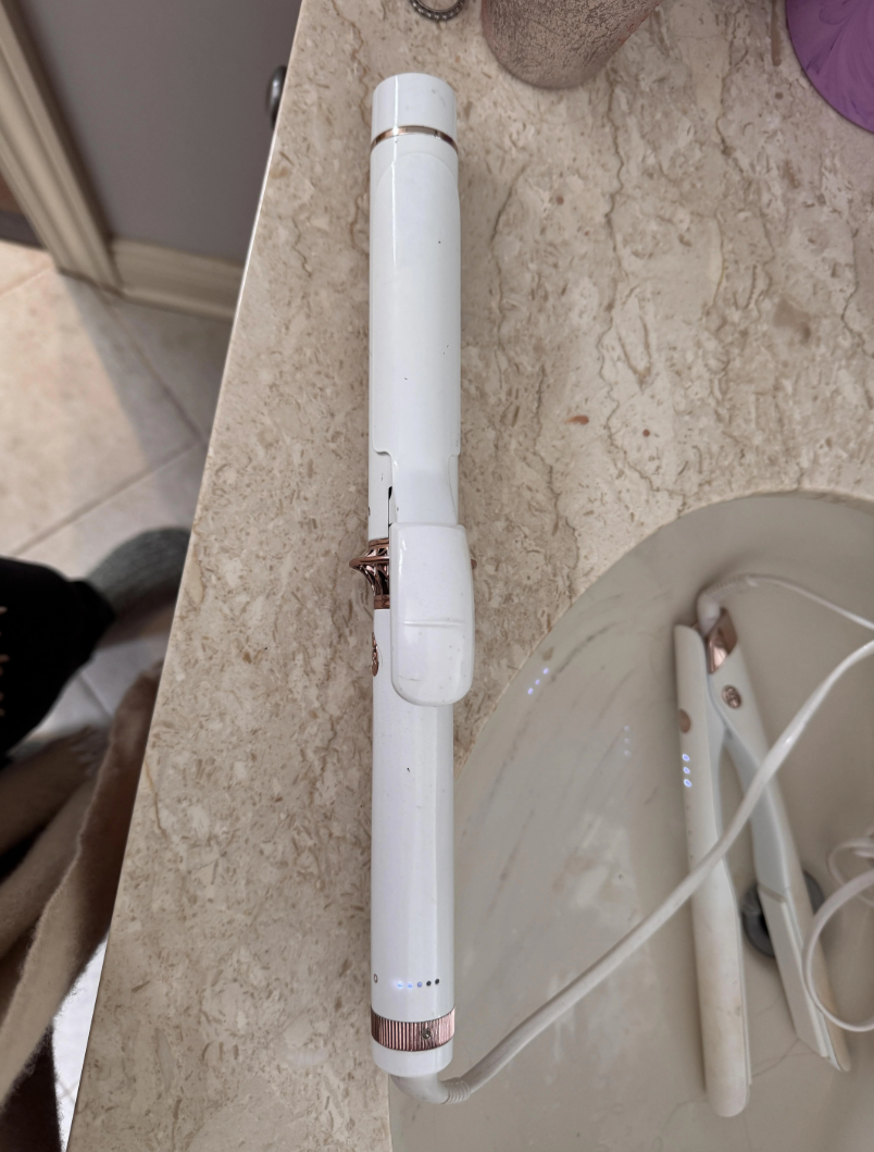 Curling iron on a bathroom countertop near a sink