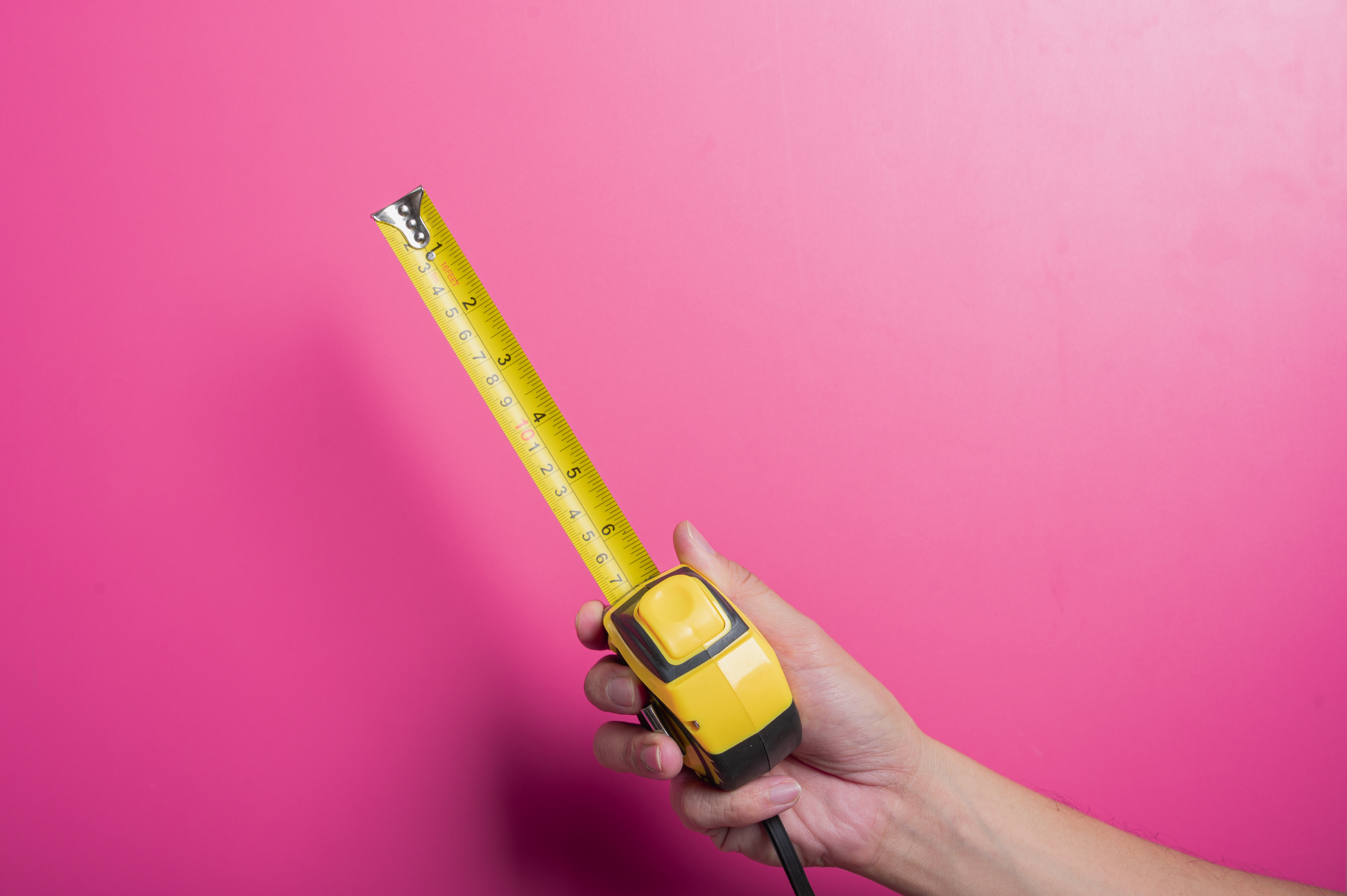 A hand holding a tape measure extended against a plain background