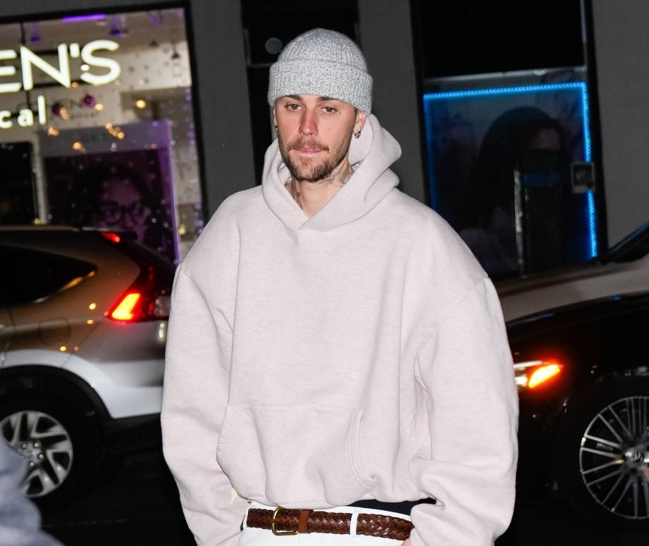 Person wearing a casual oversized hoodie, beanie, and wide pants with a braided belt, walking in an urban night setting