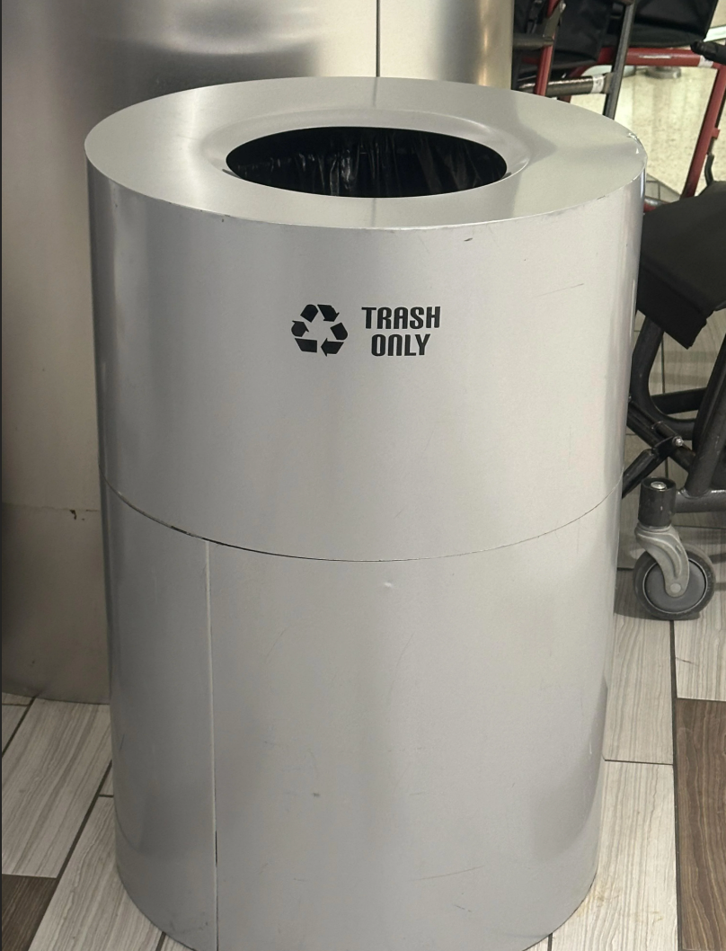 Silver trash can labeled "Trash Only" with a recycling symbol, creating confusion with mixed waste and recycling messaging