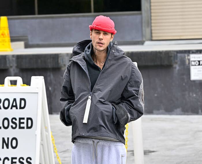 Person in a casual jacket, sweatpants, and beanie, standing near a 