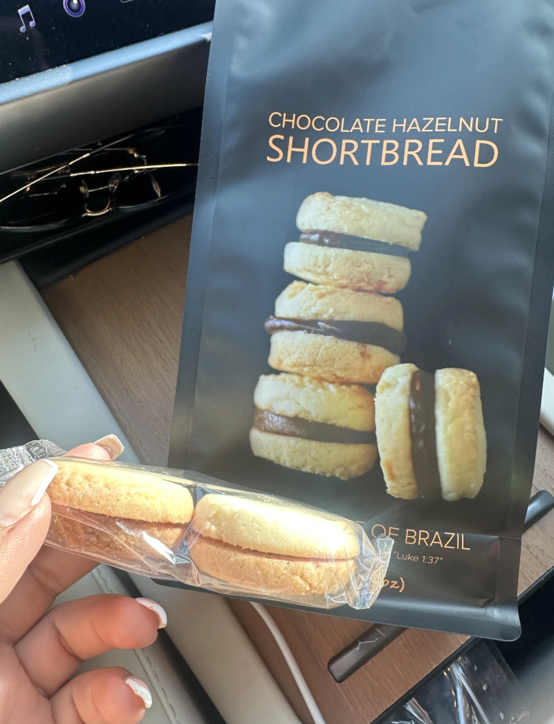 Package of chocolate hazelnut shortbread cookies with a person holding two cookies in their hand