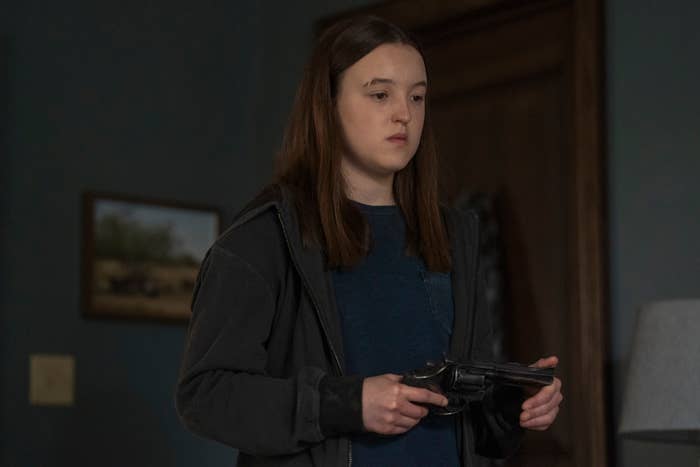 Persona joven en un interior, sosteniendo un revólver con una expresión seria