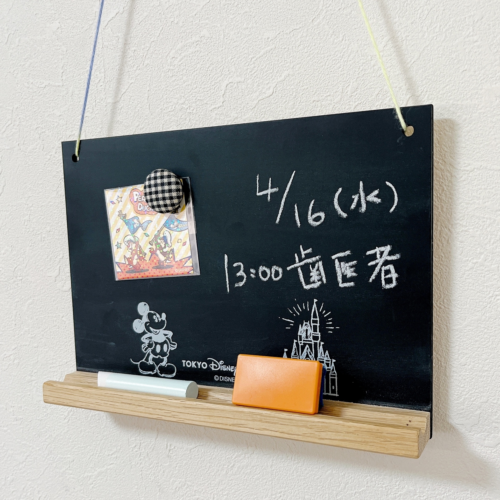 黒板に4月16日(水)、13:00、歯医者と書かれ、包装紙と小物が飾られています。ミッキーの絵もあります。