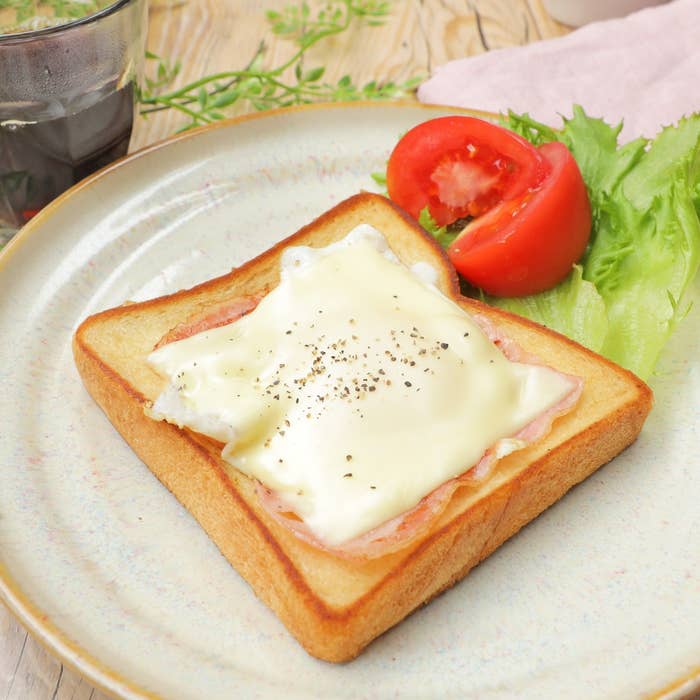 食パンにハム、溶けたチーズ、黒コショウ。添えられたレタスとトマト。