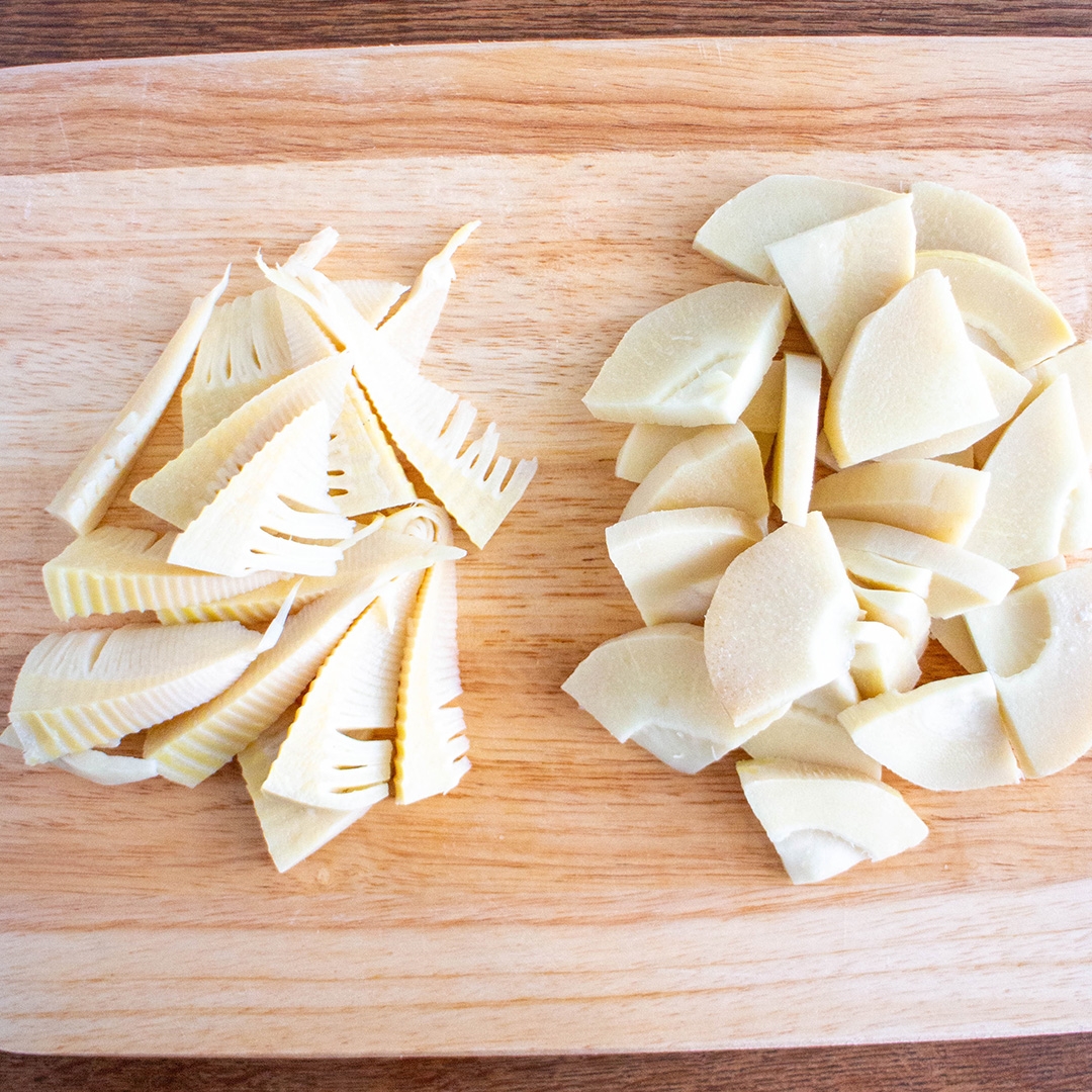 カットされた竹の子が木のまな板に2種類置かれている。左は薄くスライスされ、右は厚めに切られている。