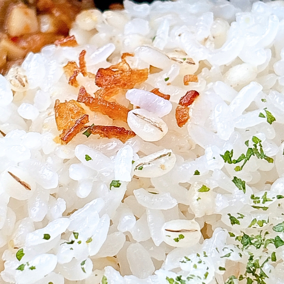 白米に揚げた玉ねぎとパセリがトッピングされた料理のクローズアップ。