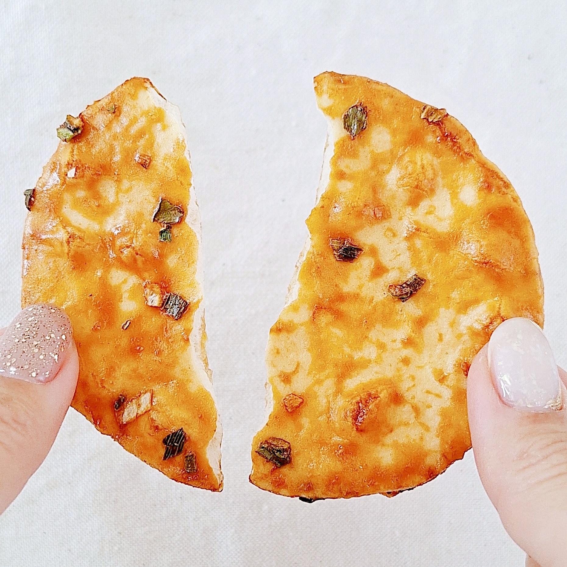 手で半分に割られた米菓子。食欲をそそるおやつ。