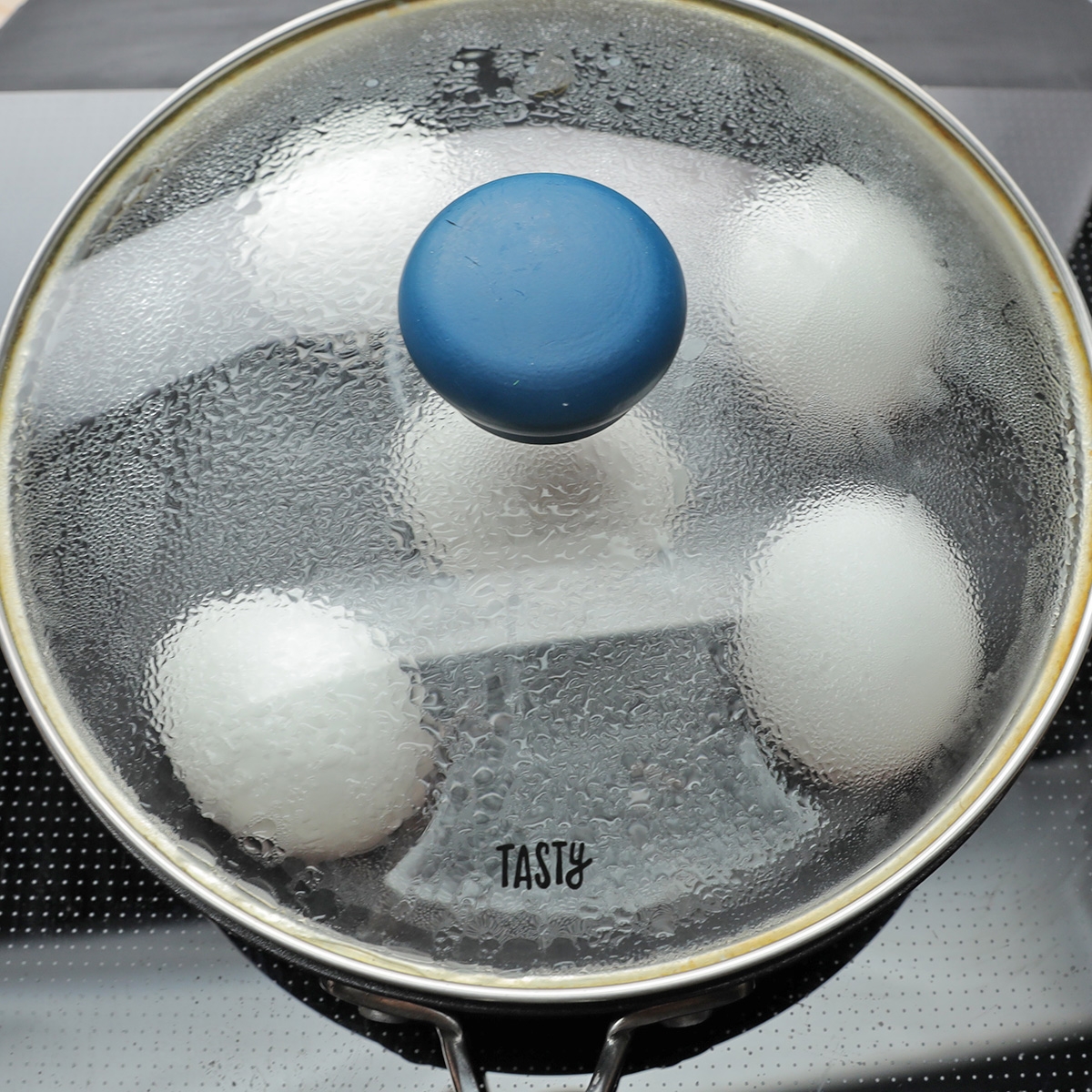 蓋のついた鍋でゆで卵を調理中。蓋に湯気がついています。